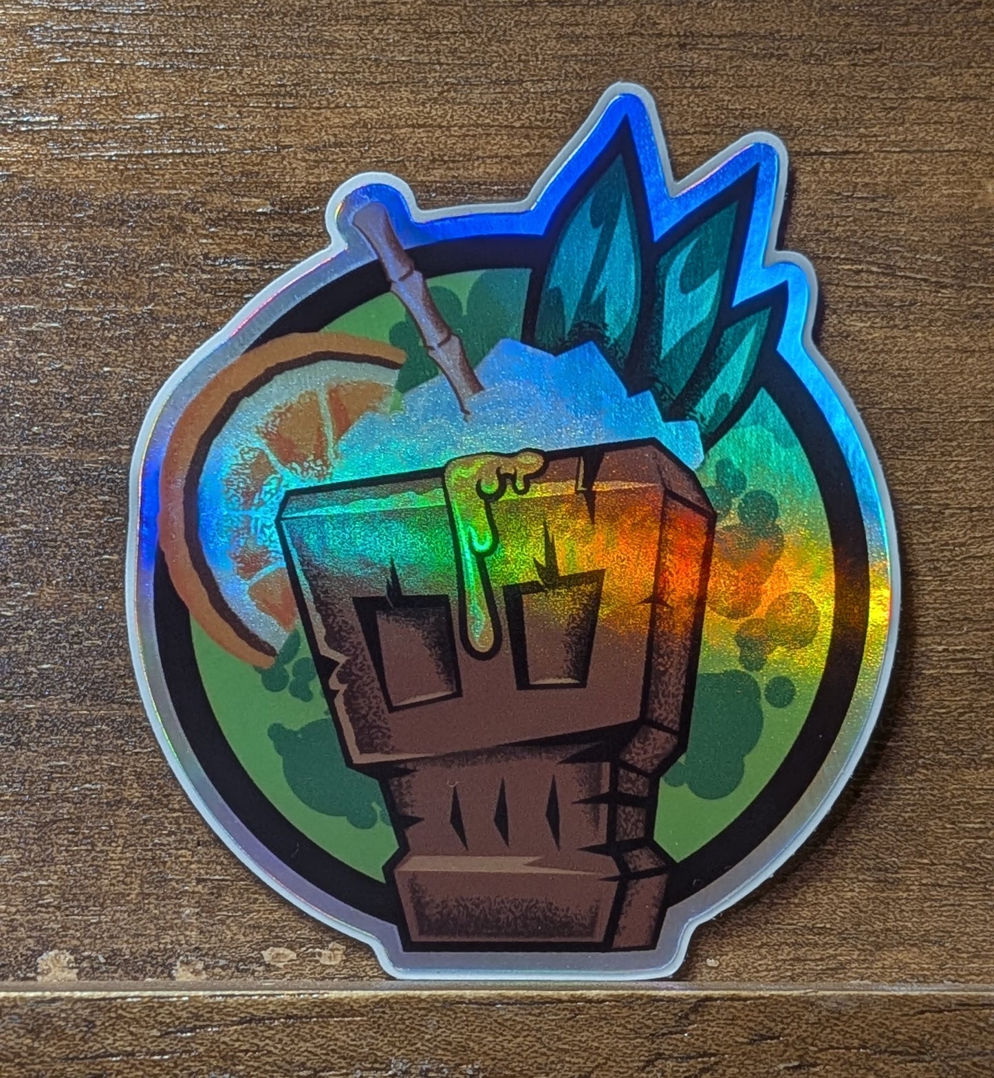 Holographic sticker with a fist and leaves on a wooden surface