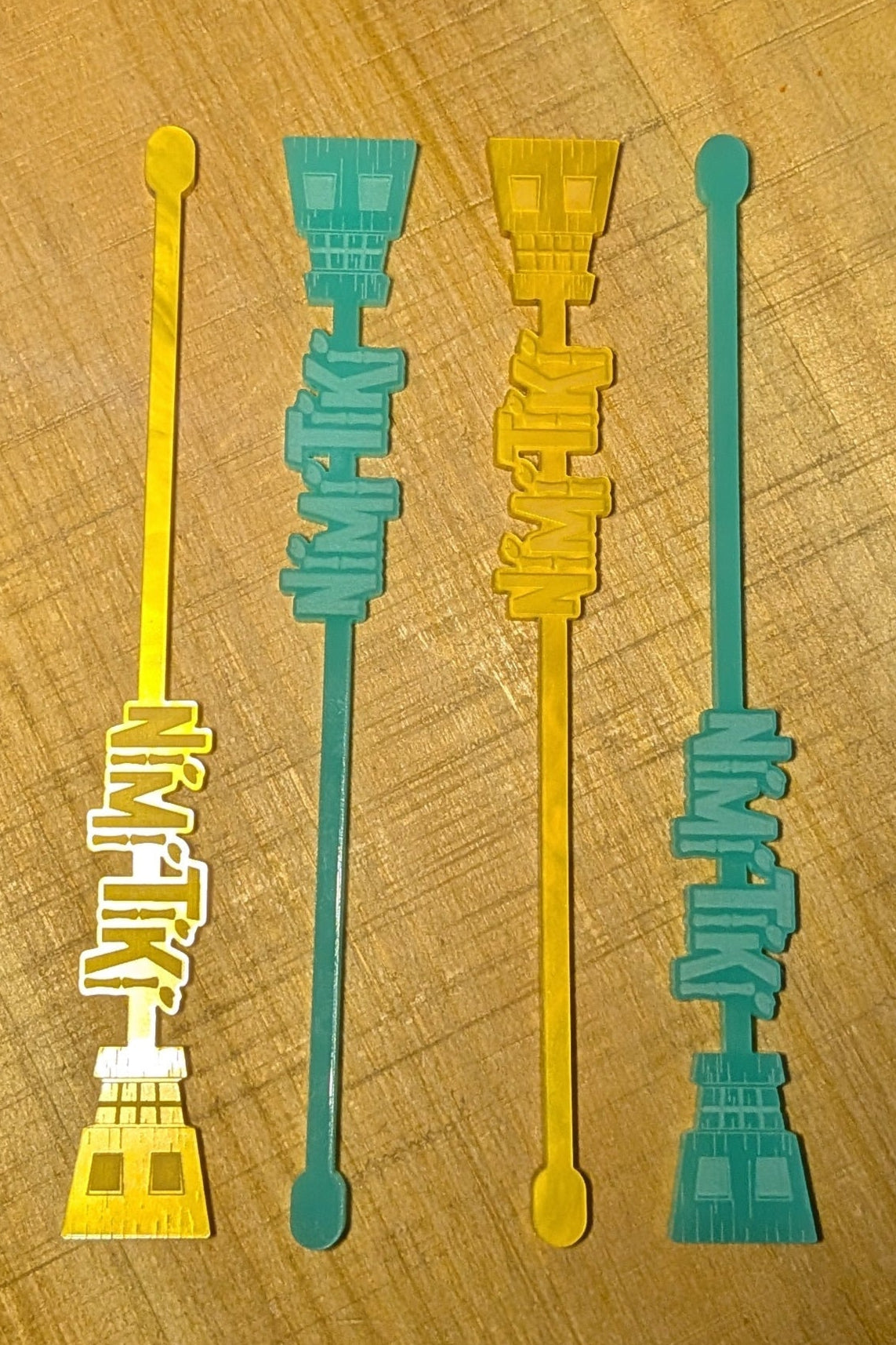 Four colorful stir sticks on a wooden surface